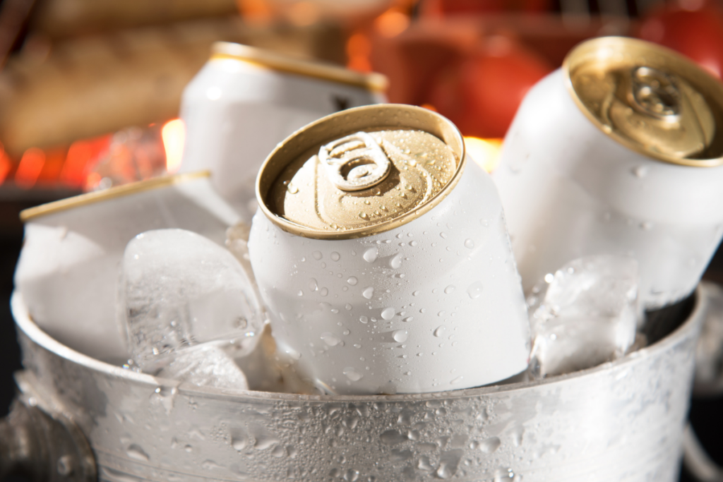 Unlabeled canned beverages chilling in a metal bucket filled with ice