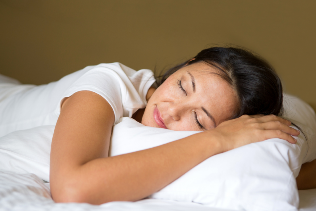 Woman sleeping on her side with her head resting on a white pillow