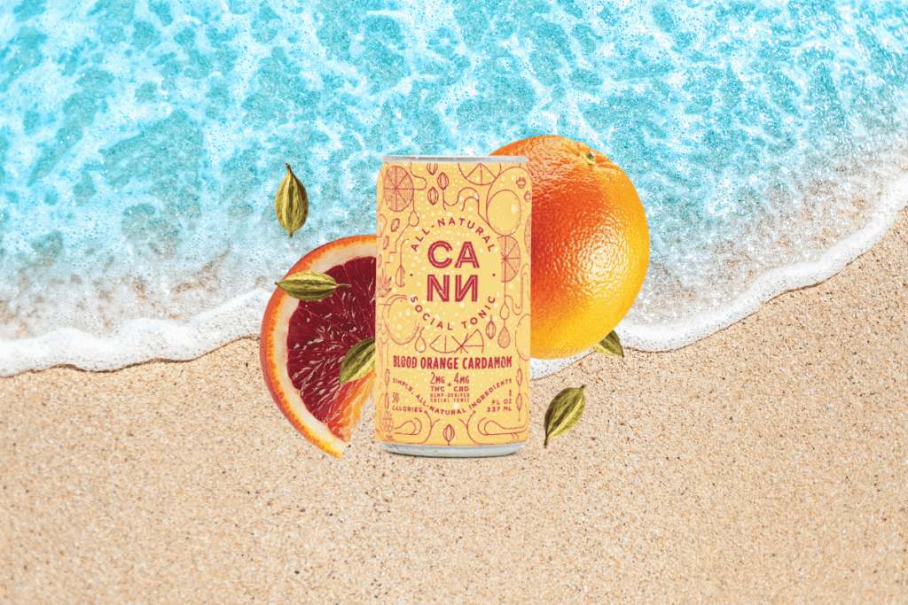 Cann Blood Orange Cardamom cannabis beverage can with orange slices on a beach background